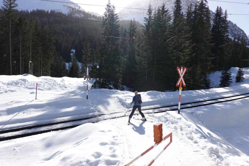Mit den Ski über den Bahnübergang.